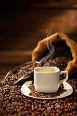 Coffee cup with smoke and coffee beans on old wooden table