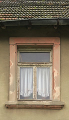 Fototapeta na wymiar Marodes renovierungsbedürftiges Fenster mit Gardinen