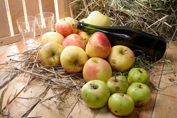 bottle of cider with some apples and straw