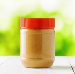 Jar of peanut butter on nature background