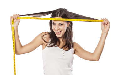 Happy attractive girl measured her hair with a tape measure
