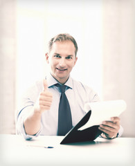 businessman with papers showing thumbs up