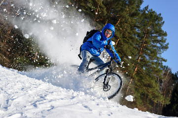 Rider cycling on mountain bicycle in the snow winter forest
