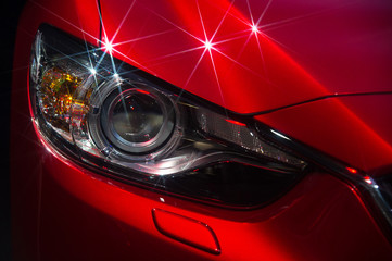 Obraz premium Hood and headlights of sport red car with silver stars