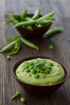 Mashed green peas and potatoes in a bowl on a wooden table