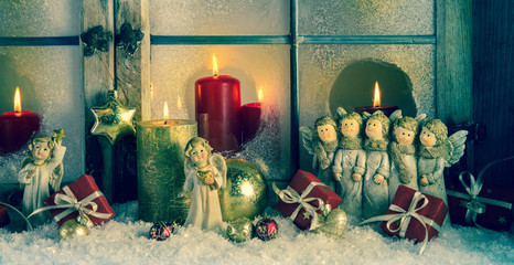 Weihnachtsdekoration mit Engel, Kerzen und Schnee im Fenster