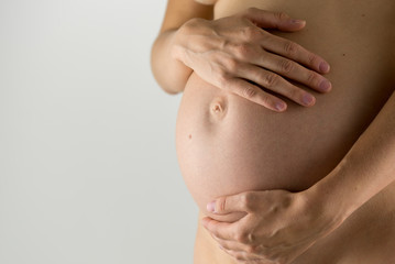Naked woman holding her pregnant belly
