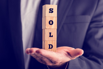 Fototapeta premium Businessman holding a sold sign