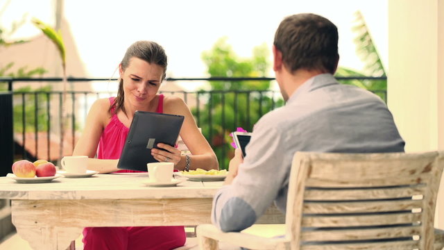Young couple watching movie on tablet computer on terrace
