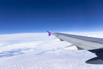 Fototapeta premium Wing of an airplane flying above the clouds
