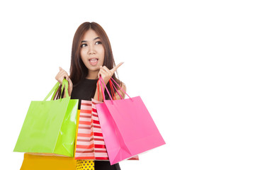 Excited Asian woman point to empty space with shopping bags