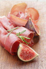 dried jamon slices with figs on wood table
