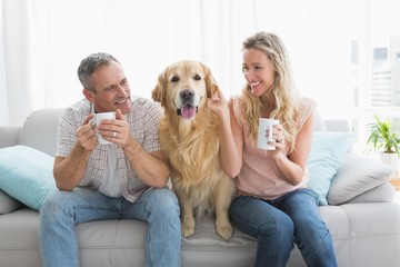 Smiling casual couple sitting on couch having coffee