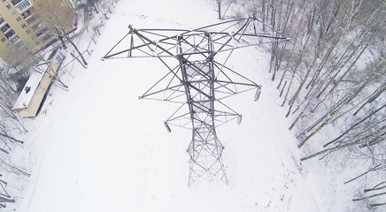 Big frosty power lines among winter snowy park near building