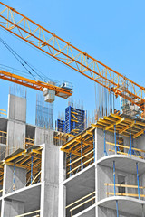 Crane and building construction site against blue sky