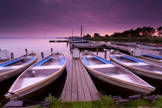 boats by pier on lake haven during sunrise