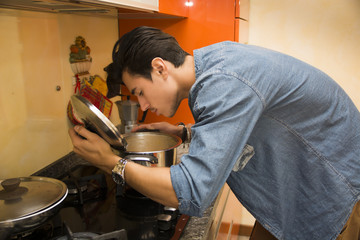 Young man smelling the food in the pot