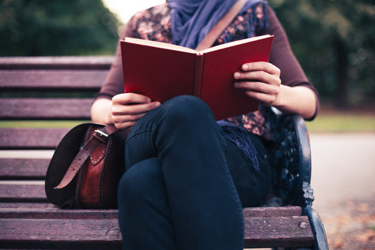 Young woman reading on park bench