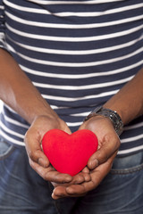 dark-skinned young man holding an object in heart shape