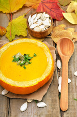 Pumpkin cream soup on rustic wooden table