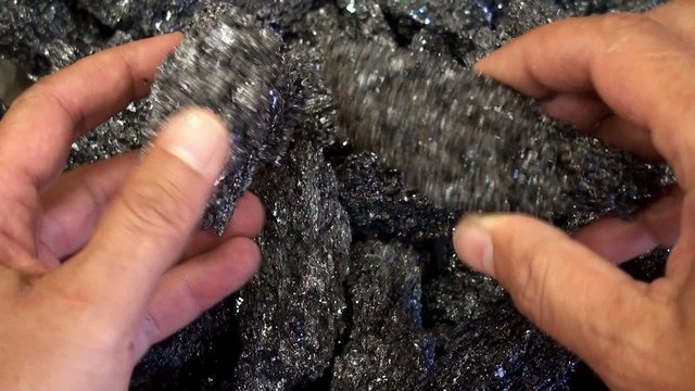 Hands with shimmering minerals from Mount Etna.