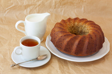 homemade banana cake on a white plate, tea and milk