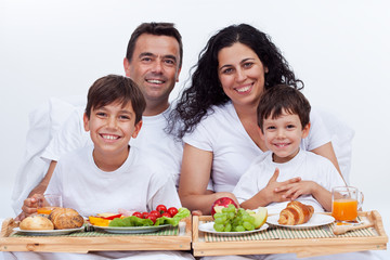 Obraz na płótnie Canvas Happy family with two kids having breakfast in bed
