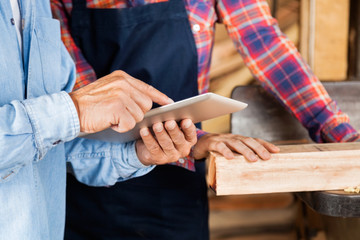 Male And Female Carpenters Using Digital Tablet