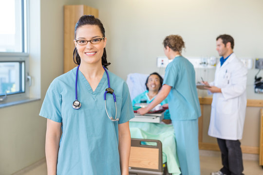 Nurse Smiling With Patient And Medical Team In Background