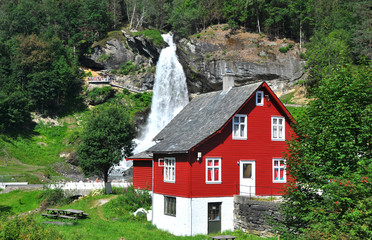 steinsdalsfossen, rotes holzhaus und wasserfall in norwegen