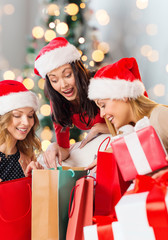 smiling young women in santa hats with gifts