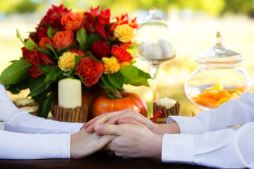 Women's and men's hands with wedding rings at a table decorated