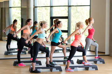 group of women with dumbbells and steppers