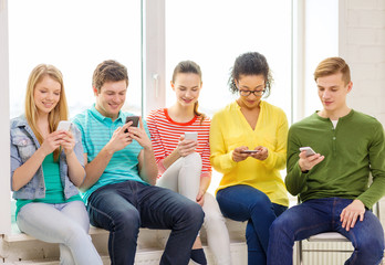 smiling students with smartphone texting at school