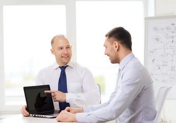 Fototapeta na wymiar two smiling businessmen with laptop in office