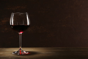 Goblet of red wine on wooden table on wooden wall background