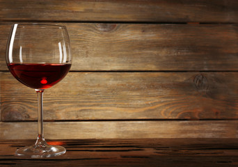 Goblet of red wine on wooden table on wooden wall background