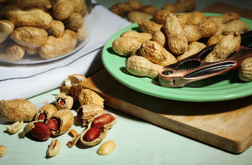Peanuts and nutcracker on plate, on wooden background