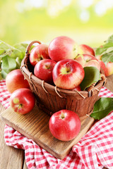 Naklejka na ściany i meble Sweet apples in wooden basket on table on bright background