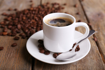 Cup of coffee and coffee beans on napkin on wooden background