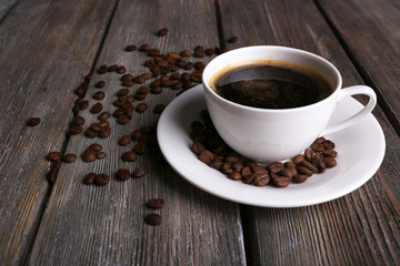 Cup of coffee and coffee beans on wooden background