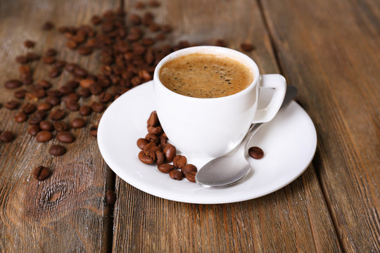 Cup of coffee with milk and coffee beans on wooden background