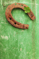 Old horse shoe,with clover leaf, on wooden background