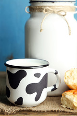 Retro can for milk and mug of milk on wooden table