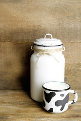 Retro can for milk and mug of milk on wooden table