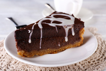 Piece of chocolate cake on plate and cup of tea on table