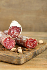 Italian salami on wooden cutting board, on wooden background