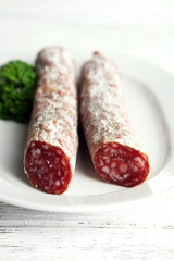 Italian salami on plate,  on wooden background