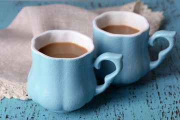 Cups of coffee with napkin on wooden table