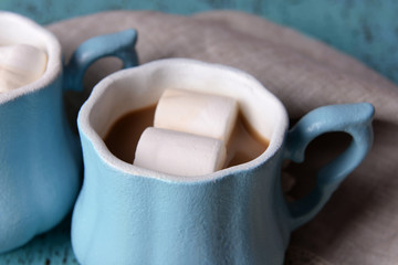 Cups of coffee with marshmallow and napkin on wooden table